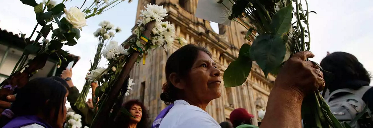 A woman holds flowers as she attends a peace march, Bogotá, Colombia.