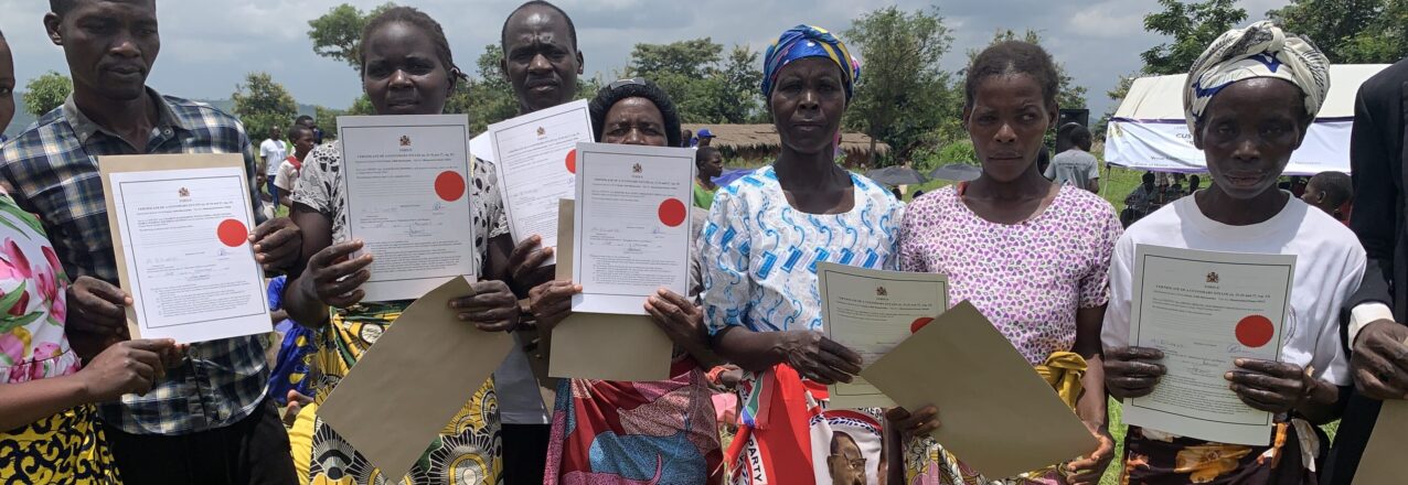 Community members in Traditional Land Management Area Mwansambo hold up customary land certificates at public ceremony with USAID and Minister of Lands in Malawi